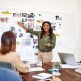 woman standing in front of a group pointing at a chart