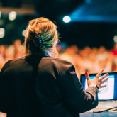 Woman delivering presentation to a large crowd