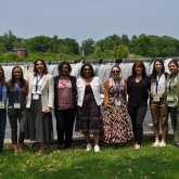 A diverse group of business women smiling at the camera in front of the Smith College waterfall.