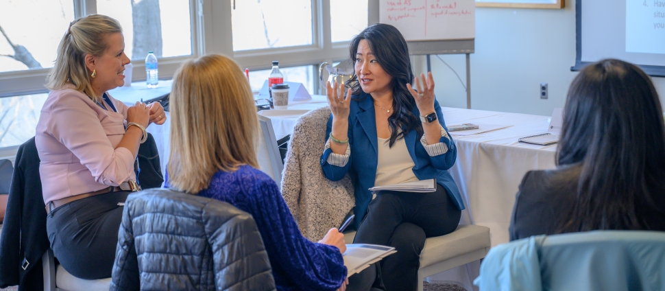 Women leaders speaking with each other during professional development event on-campus.