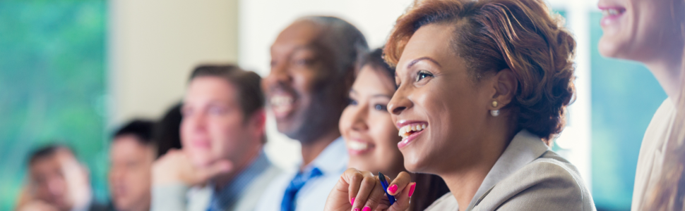 Group of diverse executive leaders listening to a presenter.