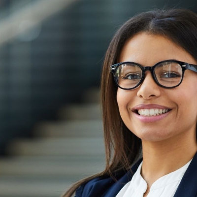 Woman with brown hair and glasses smiling wearing a business suit