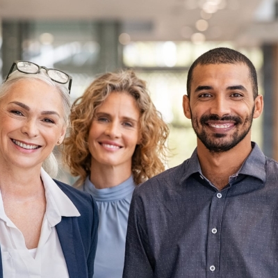 Seven business people - men and women - standing in a line facing the camera and smiling.